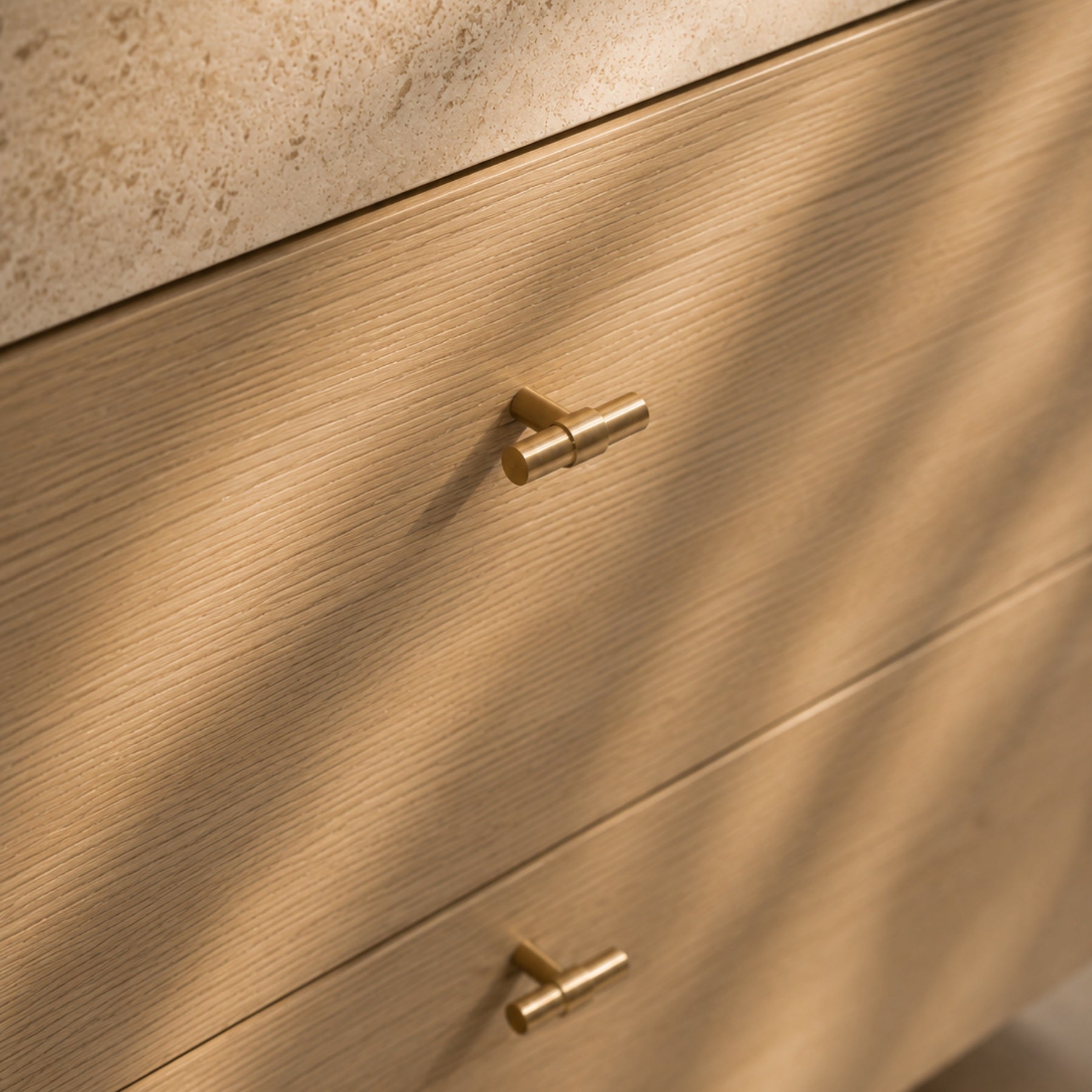 Refined brushed brass handles paired with coastal oak cabinetry and soft shadow overlays