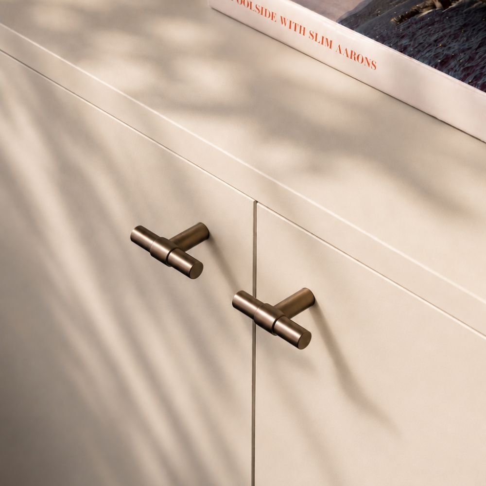 Close-up of a cabinet with bronze handles on a light wood background